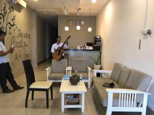 a man playing a guitar in a living room at Asiban Quay Boutique Hotel in Phnom Penh