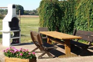a wooden table and chairs next to a pizza oven at Landhaus am Haff_ Wohnung B 8 in Stolpe auf Usedom