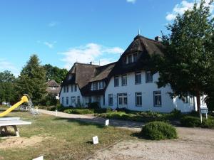 a large white house with a playground in front of it at Landhaus am Haff_ Wohnung B 8 in Stolpe auf Usedom