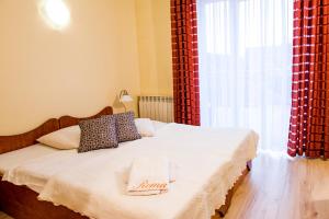 ブレンナにあるWilla Romaのベッドルーム1室(赤いカーテンと窓付きのベッド1台付)