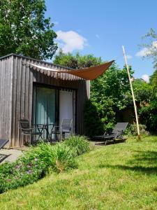 a small cabin with chairs and an umbrella in a yard at Les Cabanes de Do in Le Mans