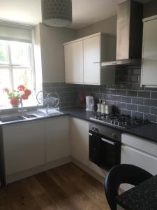 a kitchen with white cabinets and a stove top oven at Victorian Church Flat 3 in Oswestry