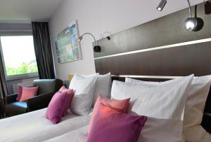 a hotel room with a bed with pink and white pillows at Hotel Uhu Garni - Superior in Cologne