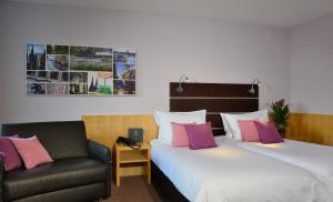 una habitación de hotel con 2 camas y una silla en Hotel Uhu Garni - Superior, en Colonia