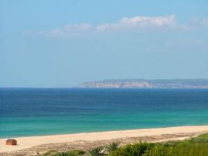 a beach with the ocean and mountains in the background at Zahara Sol Villas y Apartamentos by QHotels in Zahara de los Atunes