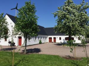 een witte kerk met rode deuren en een windmolen bij Hegnsly in Odder