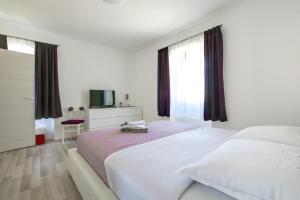 ein weißes Schlafzimmer mit 2 Betten und einem TV in der Unterkunft Apartment Maja in Pula
