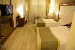 Adana Plaza Hotel في أضنة: غرفة فندقية بسريرين وتلفزيون بشاشة مسطحة