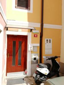 uma scooter estacionada em frente a um edifício com uma porta vermelha em Rooms Neda em Izola