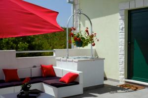 a patio with a red umbrella and a bench with red pillows at House Lucia in Brštanovo