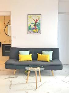 un sofá azul con almohadas amarillas en la sala de estar. en Notre Dame en Niza