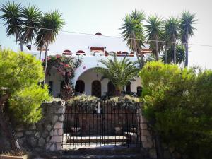 a house with palm trees in front of a gate at Apollonion Apartment Aigina in Perdhika