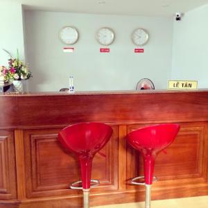 zwei rote Stühle vor einer Bar mit Uhren in der Unterkunft Khách sạn Phú An in Cà Mau