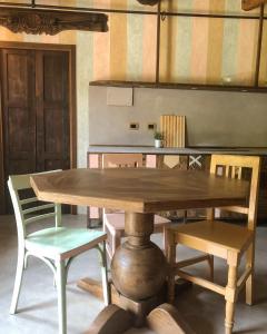 Ca' Maranghi Holiday House في بالازولو سول سينيو: طاولة وكراسي خشبية في مطبخ
