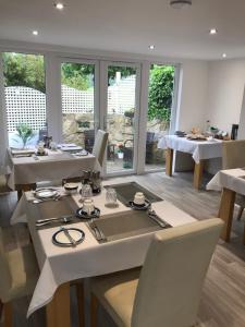 a dining room with white tables and chairs and windows at Koala Cottage in Ventnor
