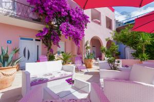 a patio with white chairs and purple flowers at Luxury Apartments Marhella & Jakov in Makarska