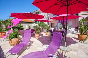 un patio con sillas moradas y sombrillas rojas en Luxury Apartments Marhella & Jakov en Makarska