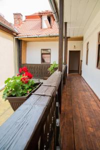 une terrasse en bois avec des fleurs rouges sur une maison dans l'établissement Musik Apartments Old Town, à Sibiu