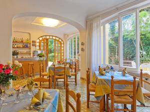 uma sala de jantar com mesas, cadeiras e janelas em Hotel Cleopatra em Ischia