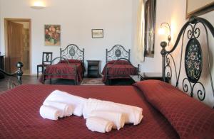 a bedroom with two beds with red sheets and white towels at Agriturismo Leone in Testa dellʼAcqua