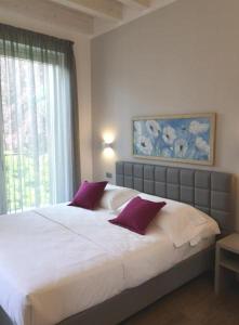 فندق كوارتشينو في كومو: غرفة نوم مع سرير أبيض كبير مع وسائد أرجوانية
