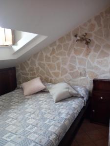 a bedroom with a stone wall with a bed with two pillows at Casa Coccorico' Pescasseroli in Pescasseroli