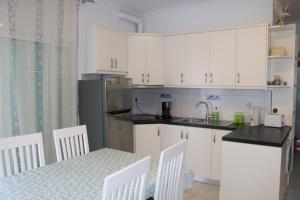 una cucina con armadi bianchi e tavolo con sedie di Robin Sea View Apartment a Sarandë