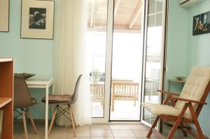 a room with chairs and a desk and a balcony at Sunny Studio in Koropi