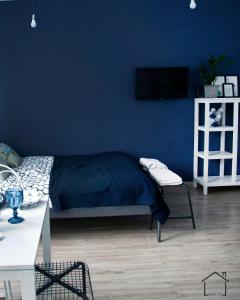 um quarto com paredes azuis, uma cama e uma mesa em Hostel 33 em Trzebinia