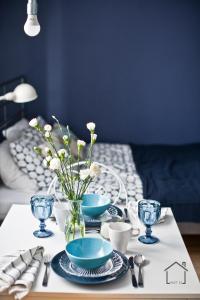 a table with plates and bowls and a vase with flowers at Hostel 33 in Trzebinia