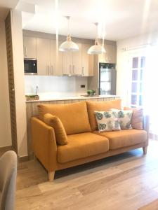 an orange couch in a living room with a kitchen at Apartament Neret II in Sort
