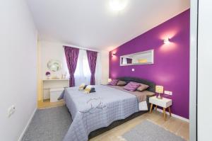 Dormitorio púrpura con cama y pared púrpura en Apartments Maraš, en Zadar