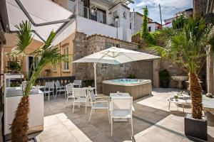 patio con mesa, sombrilla y bañera de hidromasaje en Antica Dimora Magi en Sorrento