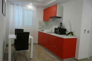 a kitchen with red cabinets and a white table at Apartments Sabioncello in Orebić