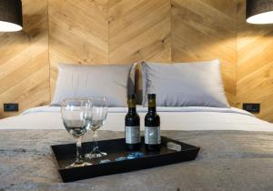 dos botellas de vino y dos vasos en una bandeja en una cama en Hotel London B&B, en Skopje