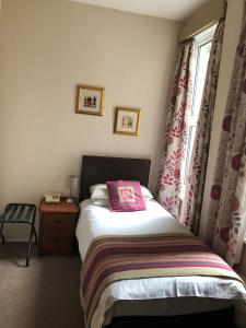 a bedroom with a bed with a pink pillow on it at The Hydro Hotel in Douglas