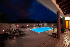 a patio with a swimming pool at night at Villa Komel with Pool in Fažana