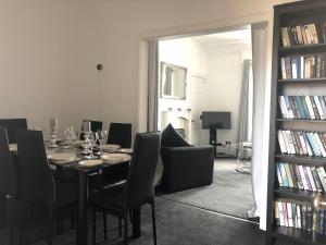 ein Esszimmer mit einem Tisch, Stühlen und einem Bücherregal in der Unterkunft Wellesley Apartment in Leven-Fife