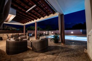 an outdoor patio with chairs and a pool at night at Villa Komel with Pool in Fažana