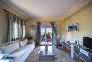 a living room with a white couch and a tv at Bella Vista Villas & Suites in Gaios