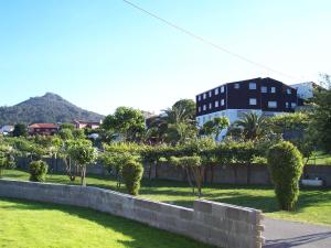 a retaining wall in a park with trees and a building at Apartamentos Blanco Y Negro in A Guarda
