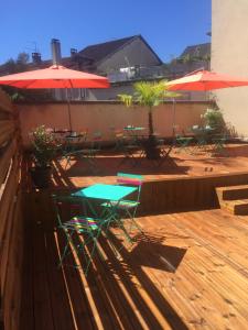 un patio avec des tables, des chaises et des parasols dans l'établissement Hotel du Touring, à Saint-Céré