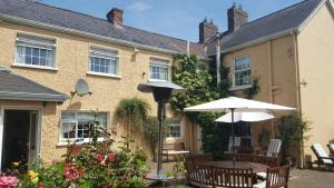 une terrasse avec des tables et des parasols en face d'une maison dans l'établissement Annalee House B&B, à Droichead an Bhuitléaraigh