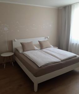 Bett in einem weißen Zimmer mit Fenster in der Unterkunft Apartment Graz Murpromenade in Graz