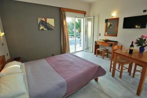 1 dormitorio con cama, mesa y escritorio en Athena Hotel en Georgioupolis