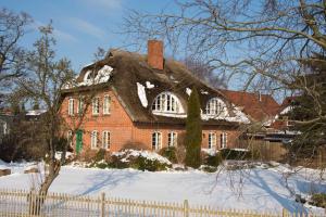 ミデルハーゲンにあるLandhaus am Deichの屋根に雪が積もったレンガ造りの家