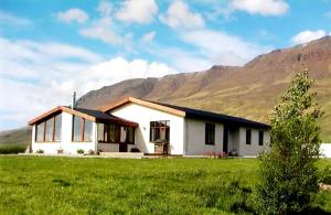 a white house in a field with a mountain at Flugumýri 2 in Varmahlid