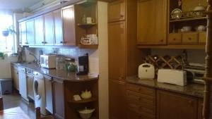 eine Küche mit Holzschränken und einer Arbeitsplatte in der Unterkunft Habitacion Privada en Piso Familiar in Pontevedra
