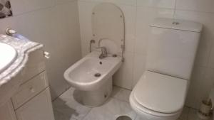 La salle de bains blanche est pourvue de toilettes et d'un lavabo. dans l'établissement Habitacion Privada en Piso Familiar, à Pontevedra