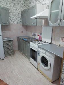 a kitchen with a stove and a washing machine at Nikos Guest House in Adler